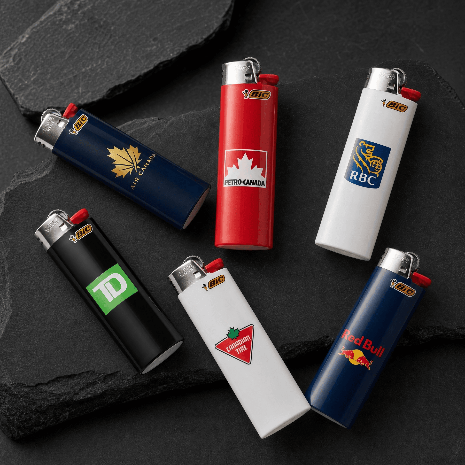 Collection of branded lighters with company logos on black surface.